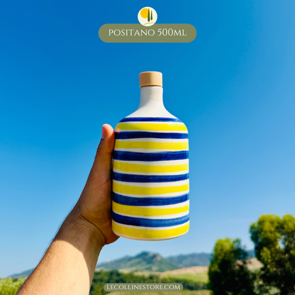 Handcrafted blue and yellow striped ceramic bottle with cork stopper, held in hand, inspired by Mediterranean coastal decor.