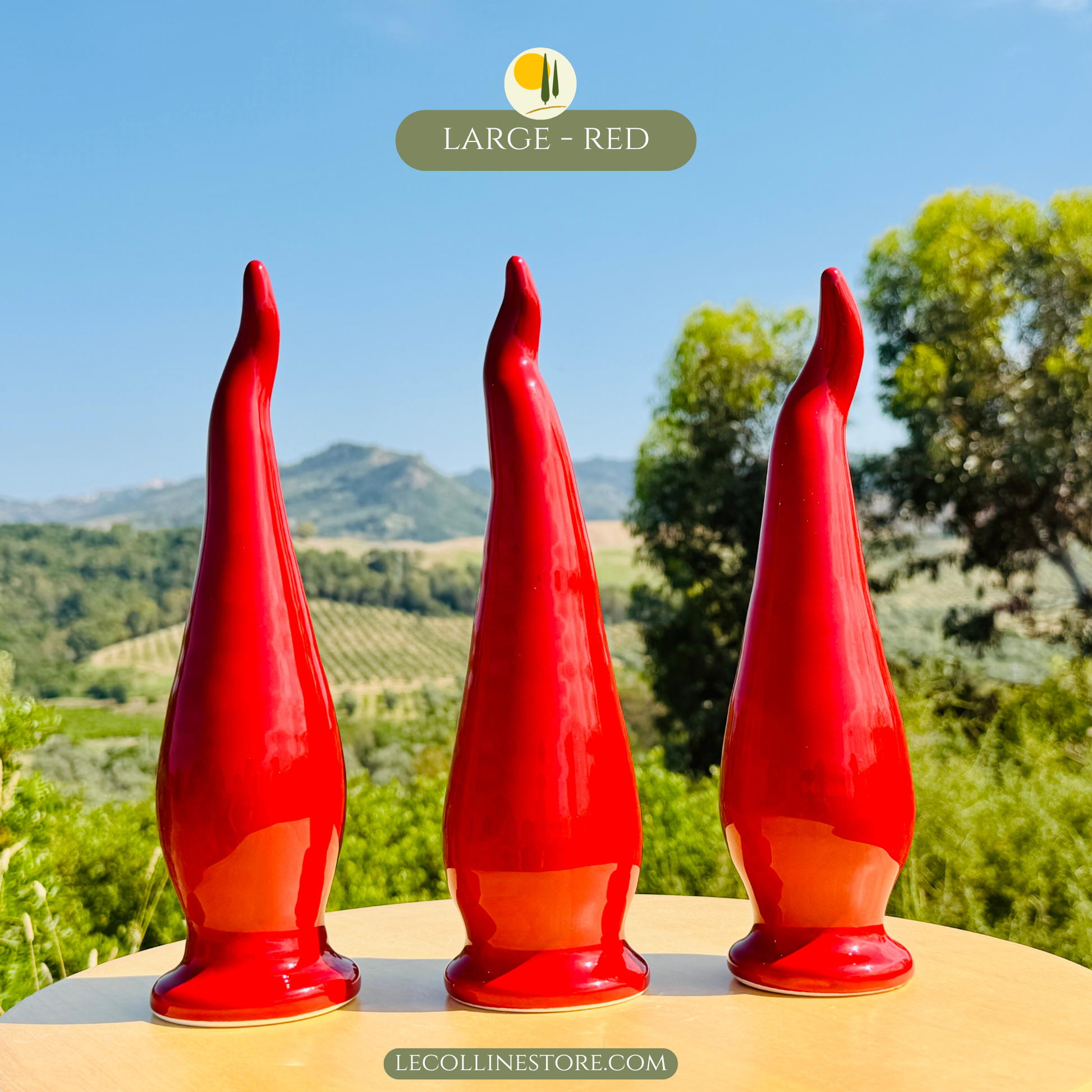 Three large red ceramic peperoncino chili pepper lucky horns with glossy handcrafted finish arranged together as a statement decor set. Bold Italian-inspired home accents photographed in natural outdoor light.