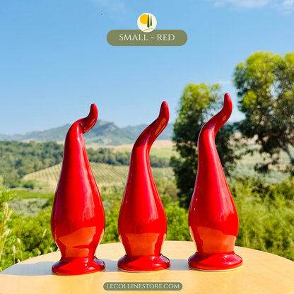 Three small red ceramic lucky horns arranged as a coordinated decorative set. Handcrafted ceramic home decor pieces with glossy finish and sculptural design, photographed in natural sunlight.