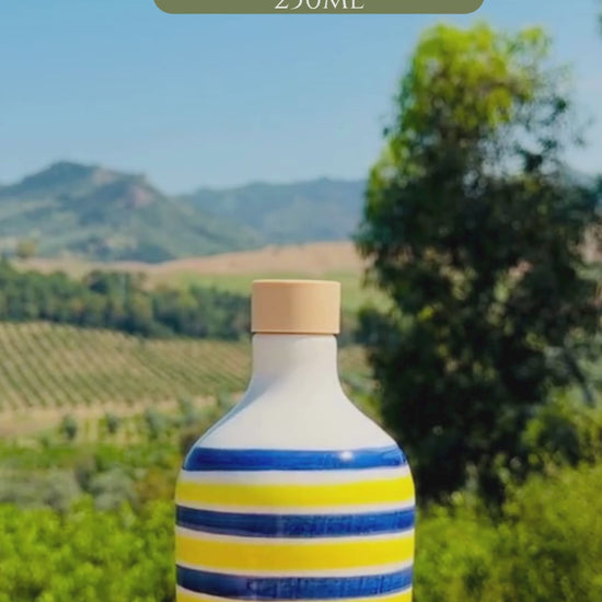 video of a Large and small ceramic bottle with alternating blue and yellow stripes and glossy handcrafted finish, displayed outdoors.