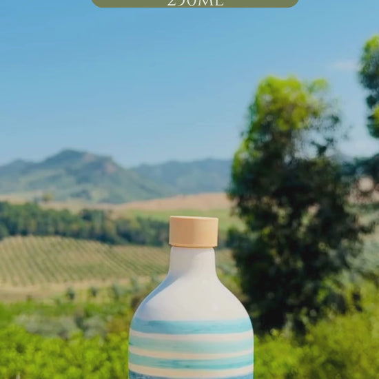 video of two Handcrafted blue striped ceramic bottles with cork stopper, displayed outdoors against vineyards and Mediterranean hills.